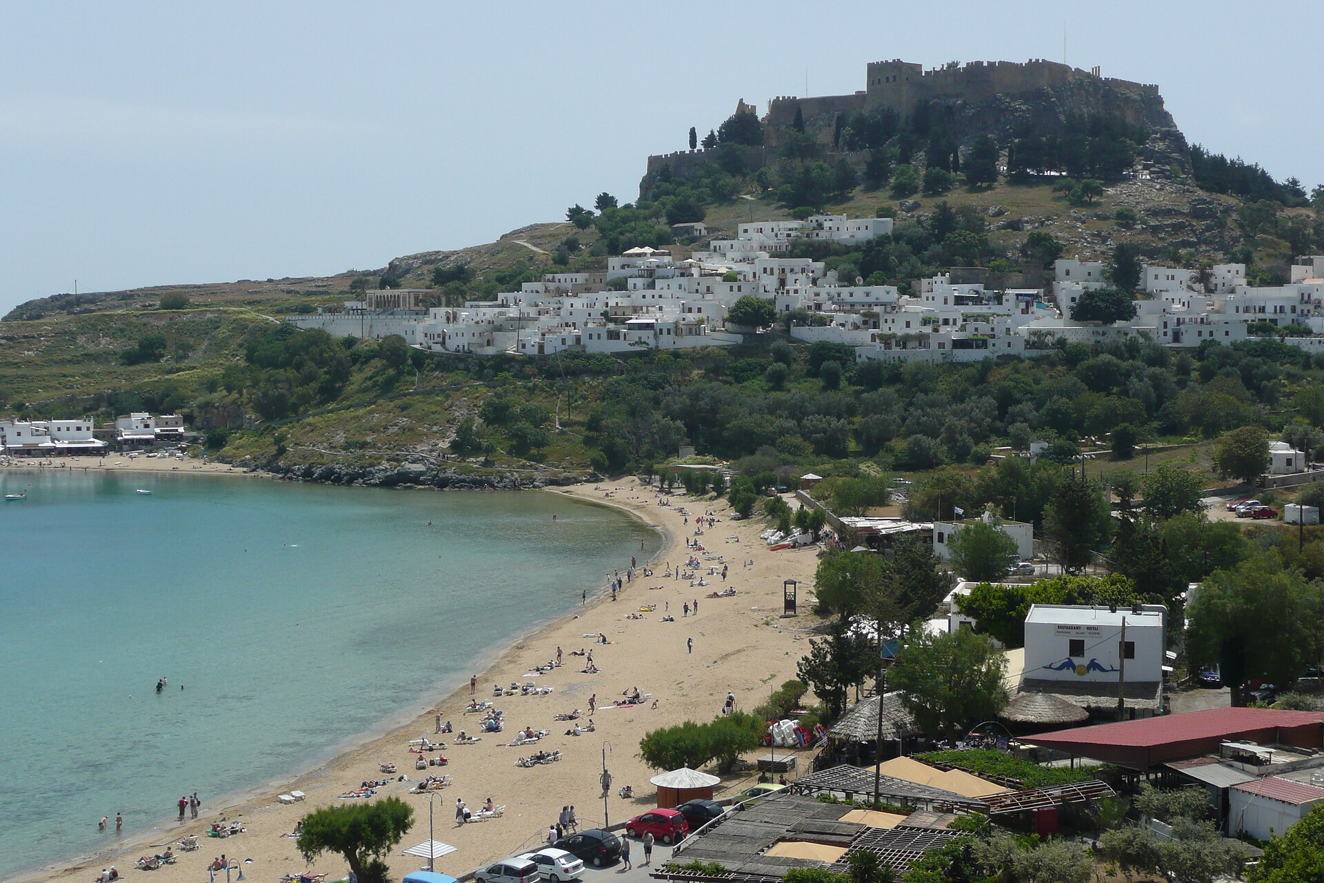 Plaża Lindos na Rodos — biały piasek i ruiny akropolu na klifie nad zatoką